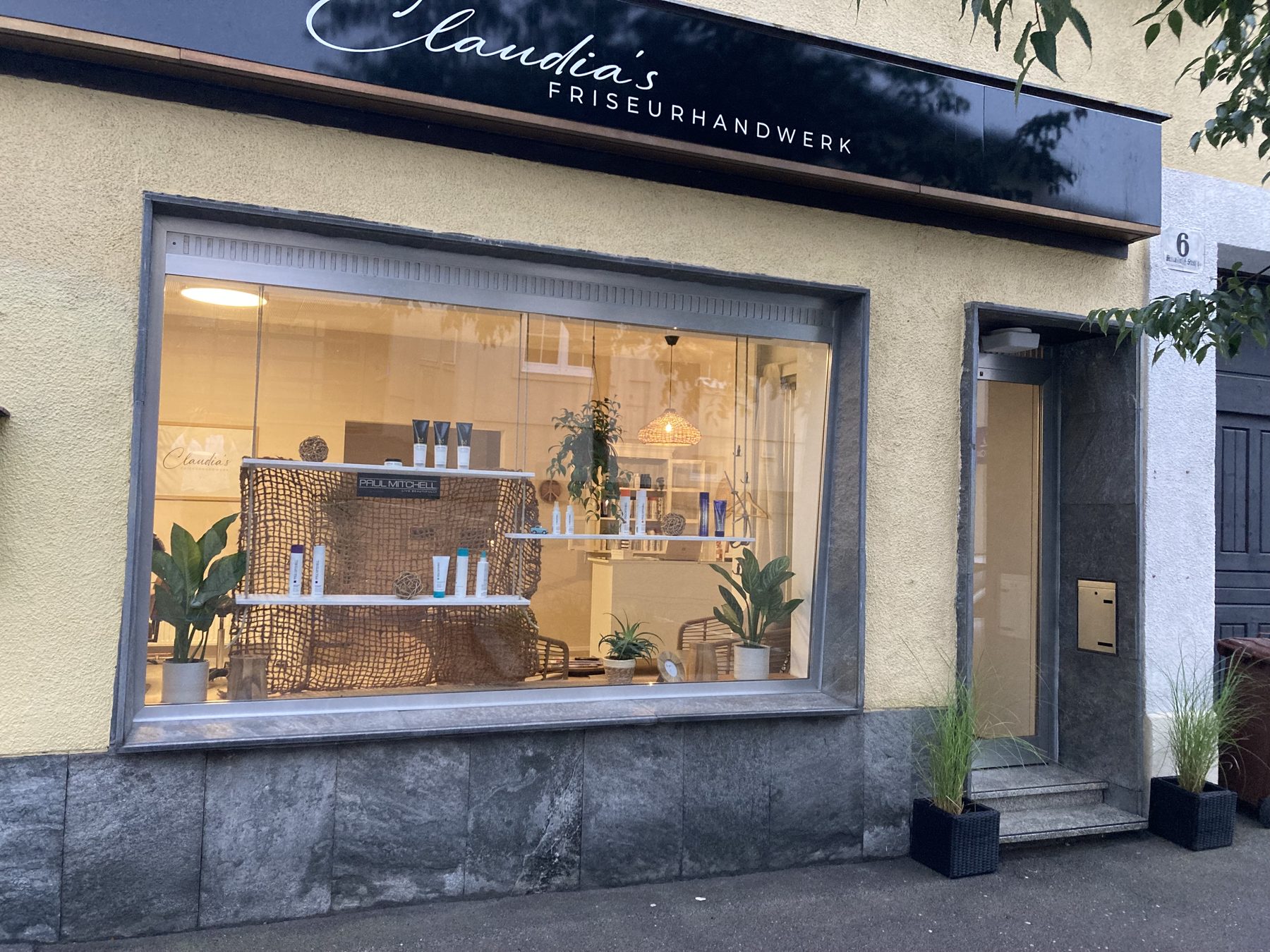 Beleuchtetes Schaufenster von Claudia's Friseurhandwerk am Abend